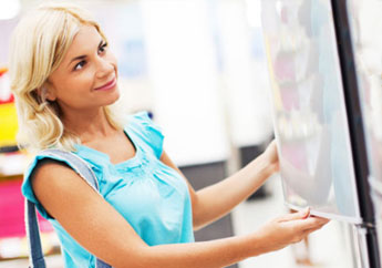 A woman looks at a refrigerator.