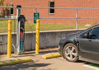A gray electric car charging at an electric vehicle charging station