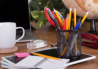 An office space showing a laptop, coffee cup, and various office supplies