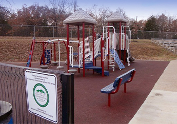 Outdoor playground with red metal supports and tan canopies