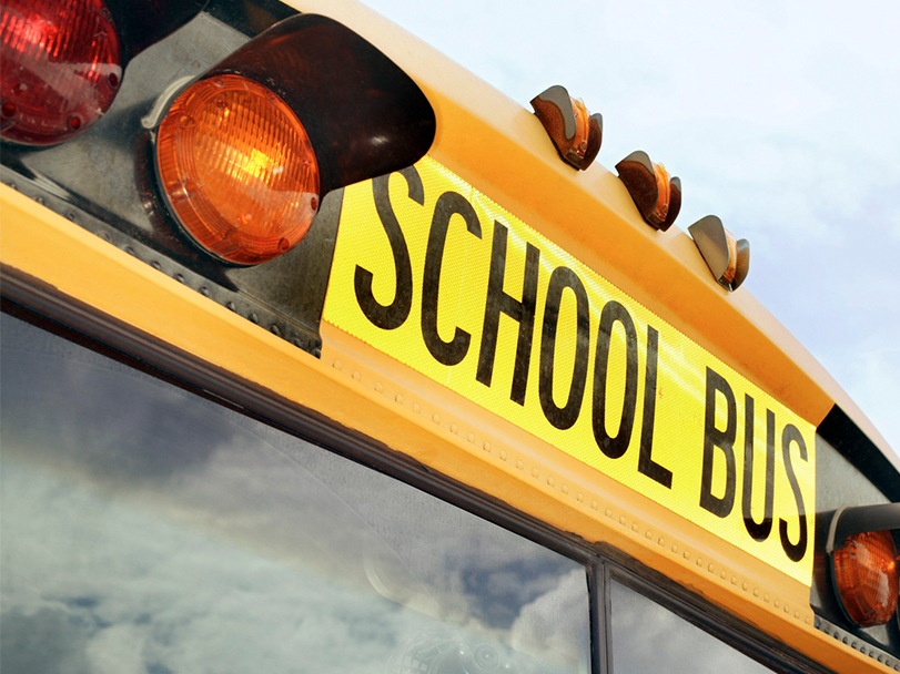 The outside of a generic yellow school bus, including the front top caution lights with the words "School Bus" 