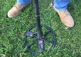 Person using a metal detector in MoStateParks looking for hidden treasures underground..