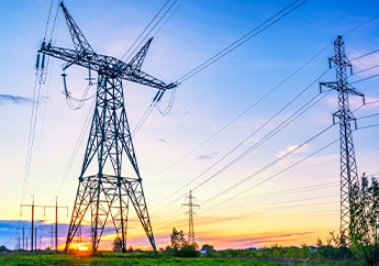 High voltage power lines and support towers in a country setting at sunset