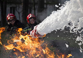 Two firefighters extinguishing a fire with aqueous film forming foam