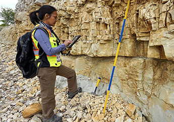 MoDNR geologist standing in front of a rock formation, writing notes in a field notebook. 