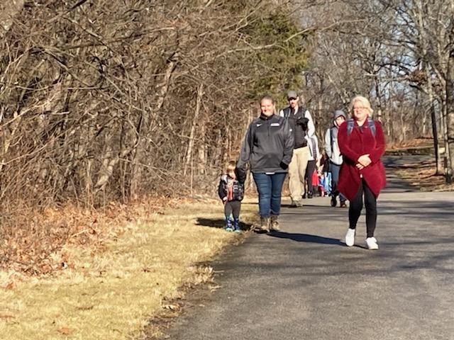 Group of people hiking along a paved trail. 