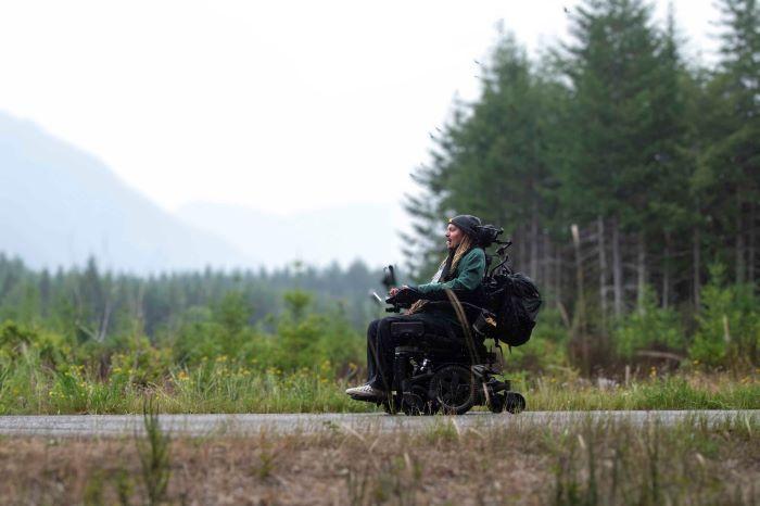 Man in powered wheelchair on paved trail.