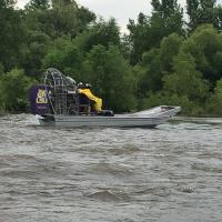 Environmental emergency response staff using contract air boats to remove orphan containers from flood waters.