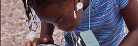A young girl in a blue and purple shirt drinking water from a water fountain