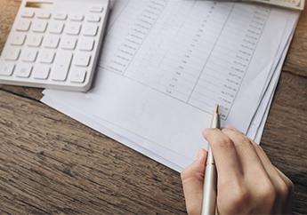 A person calculating numbers from a spreadsheet