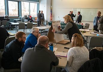 Department staff talking one-on-one with individuals at a meeting