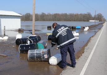 A department employee collecting abandoned drums during a flooding event