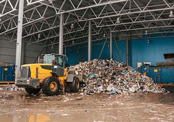 Heavy machinery moving solid waste inside a transfer station