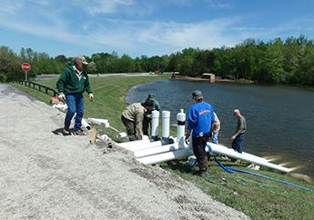 Several individuals examining a dam's drain outfall