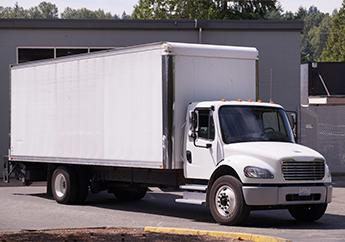 White box truck parked in front of a building