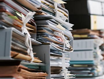 Several stacks of 3-ring binders, expandable files and other documents on a table