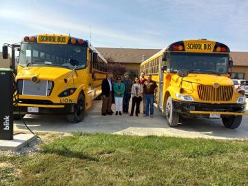 Several people standing between two school buses.