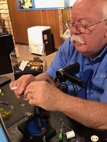 Gentleman is tying a fly using a light and enlarger. 