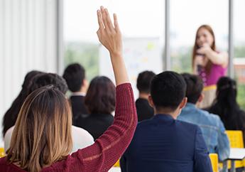 A yound woman raising her hand in a group meeting.