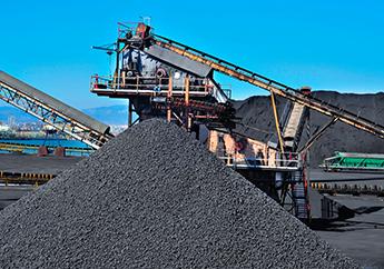 A mound of mined coal in front of a coal handling system at a coal plant.