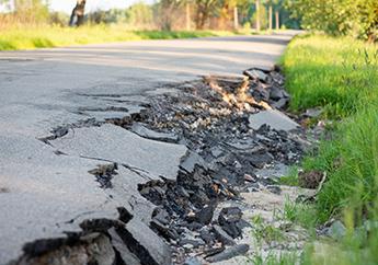 Destroyed edge of asphalt pavement on a rural road caused by flood water